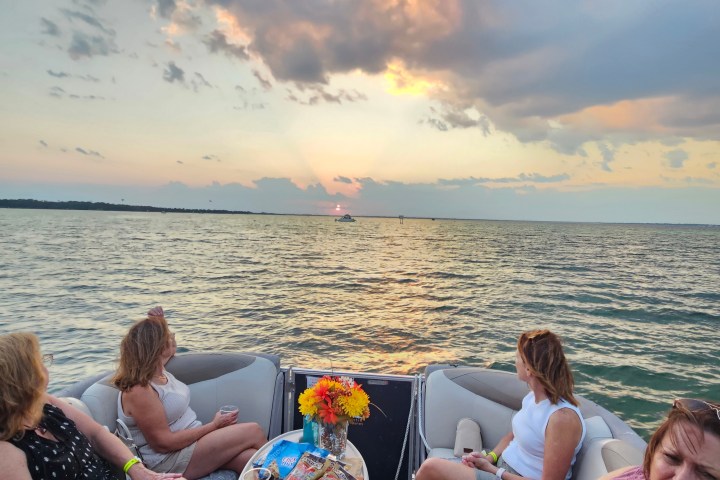 Four women on a boat watching sunset over the ocean.
