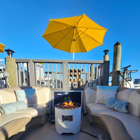 Outdoor seating with fire pit, yellow umbrella, and blue sky.