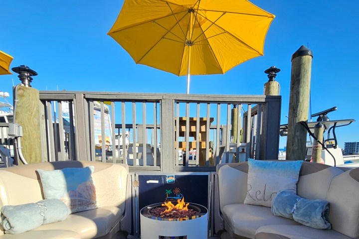 Outdoor seating with fire pit, yellow umbrella, and blue sky.