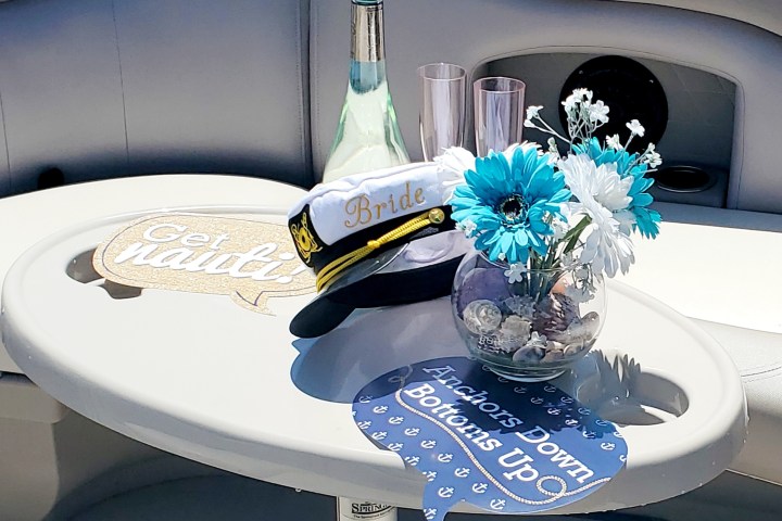 Boat table with captain hat, flowers, wine bottle, and nautical-themed signs.