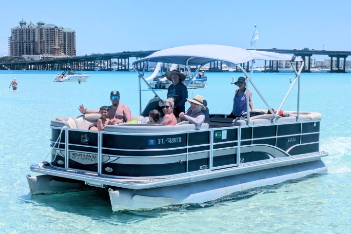 Group of people on a pontoon boat in clear blue water.