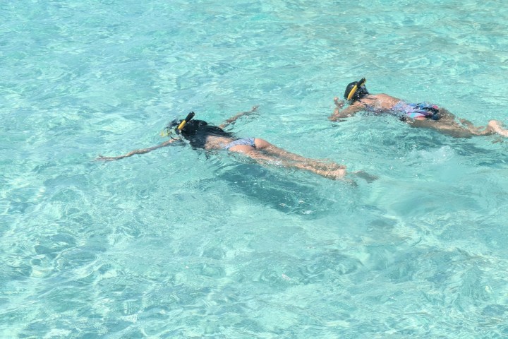 Two people snorkeling in clear turquoise water.
