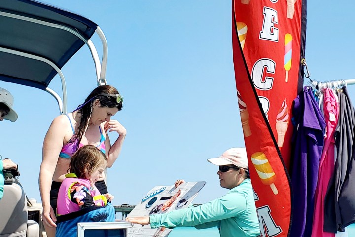 People on a boat with an ice cream flag, selecting items from a menu.