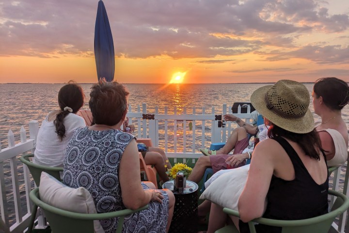 People seated on a boat watching a sunset over the ocean.