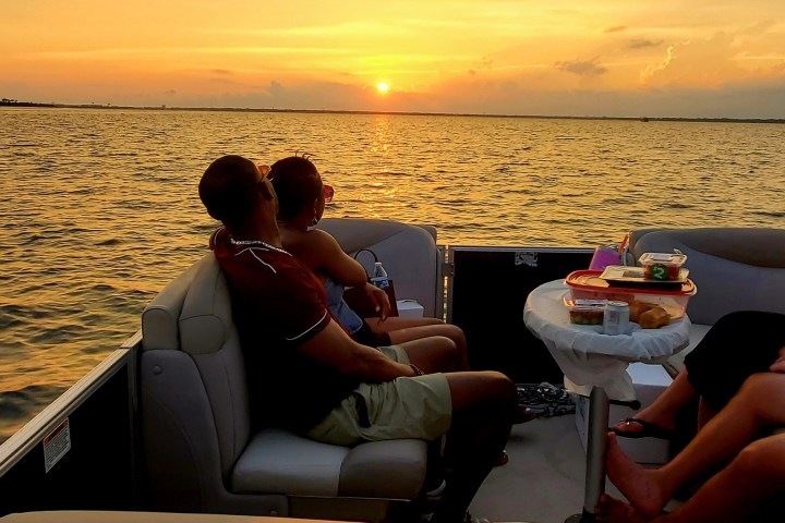 People on a boat watching a sunset over the water.