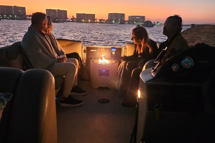 People on a boat at sunset, city skyline in the background.