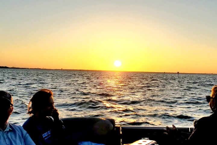 People on a boat watching a sunset over the ocean.