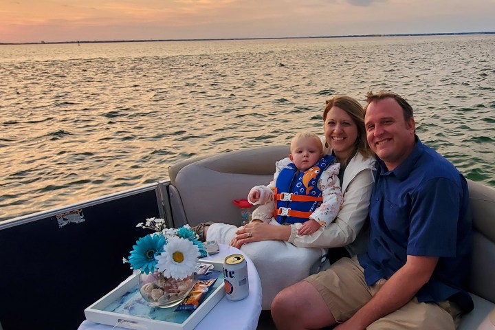 Family on a boat at sunset, with water and sky in the background.