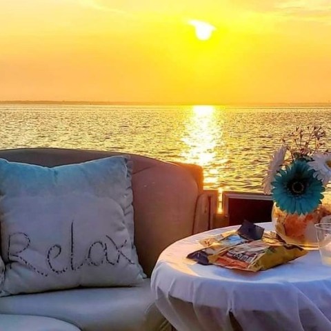 Sunset over water with snacks and drinks on a table.