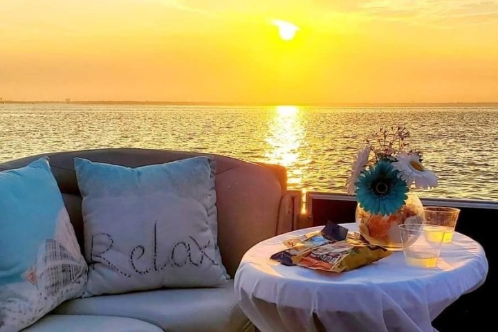 Sunset over water with snacks and drinks on a table.