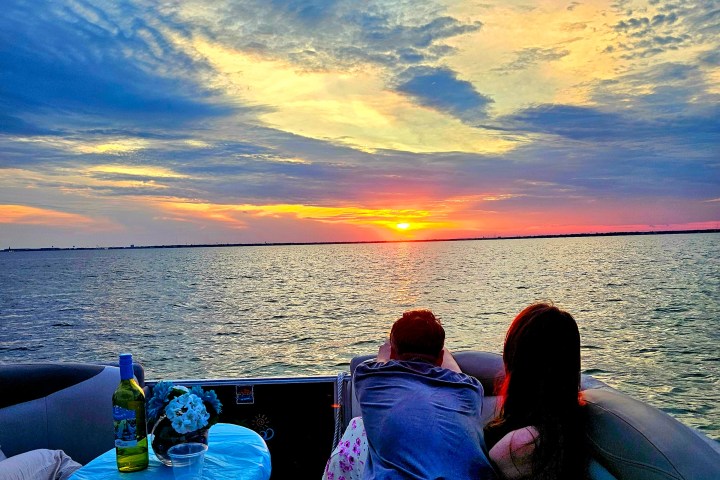 Couple on a boat watching a vibrant sunset over the ocean.