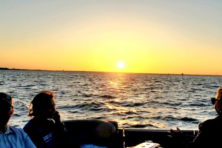Silhouettes of people on a boat at sunset on a calm sea.