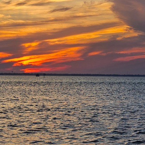 Colorful sunset over calm ocean with dramatic clouds.