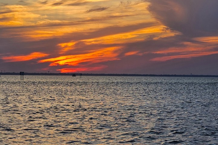 Colorful sunset over calm ocean with dramatic clouds.