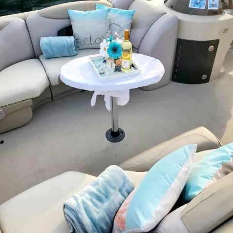 Cozy boat seating with pillows, a blanket, and a small table holding flowers and wine.