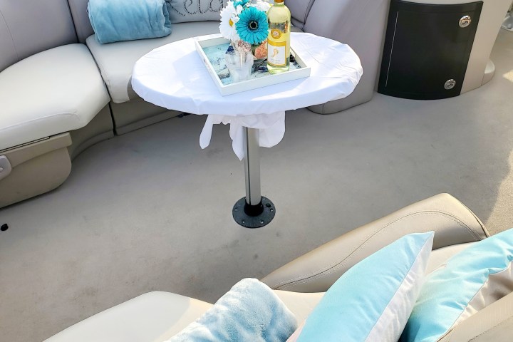 Cozy boat seating with pillows, a blanket, and a small table holding flowers and wine.