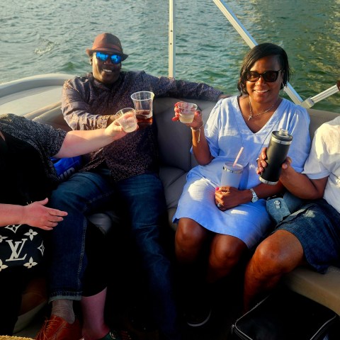 Four people smiling and holding drinks on a boat.