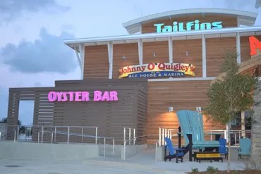 Building with signs for TailFins and Oyster Bar, plus large outdoor chairs.