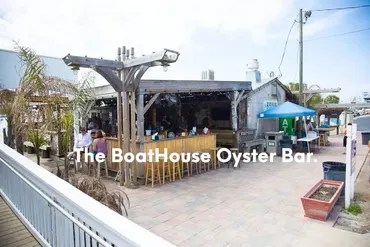 Outdoor oyster bar with wooden seating and an awning.